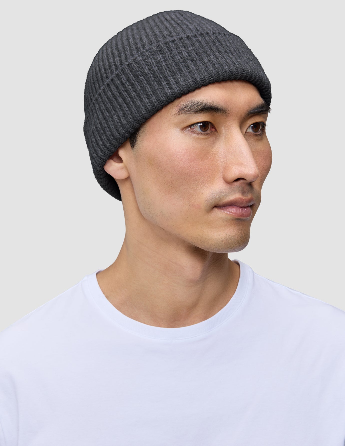 En person, der bærer en mørkegrå Beanie Dark Grey, en ribstrikket hue i merinould i dansk design.